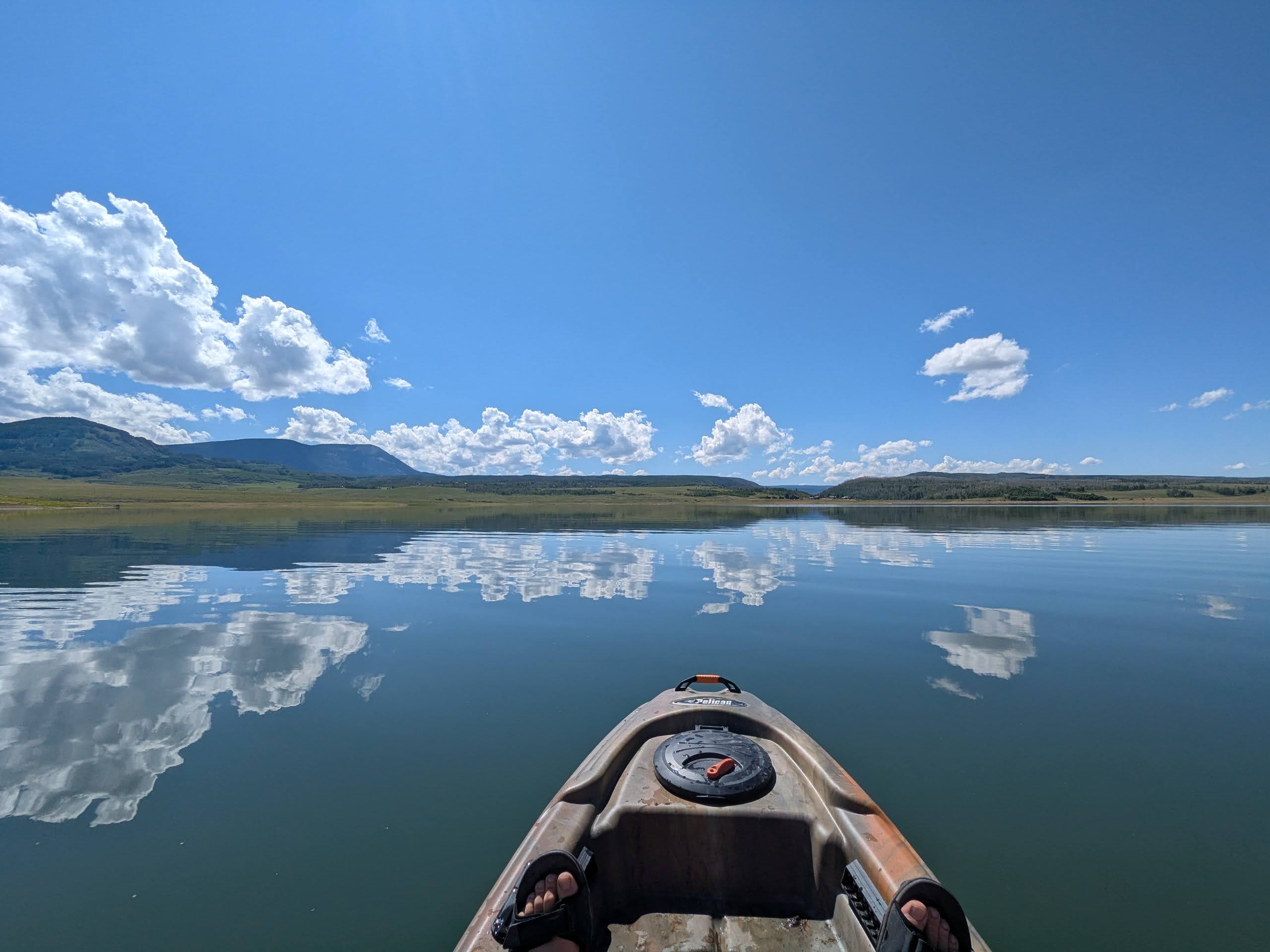 Kayaking on the glassy surface of Groundhog Lake, clouds mirrored in the water
